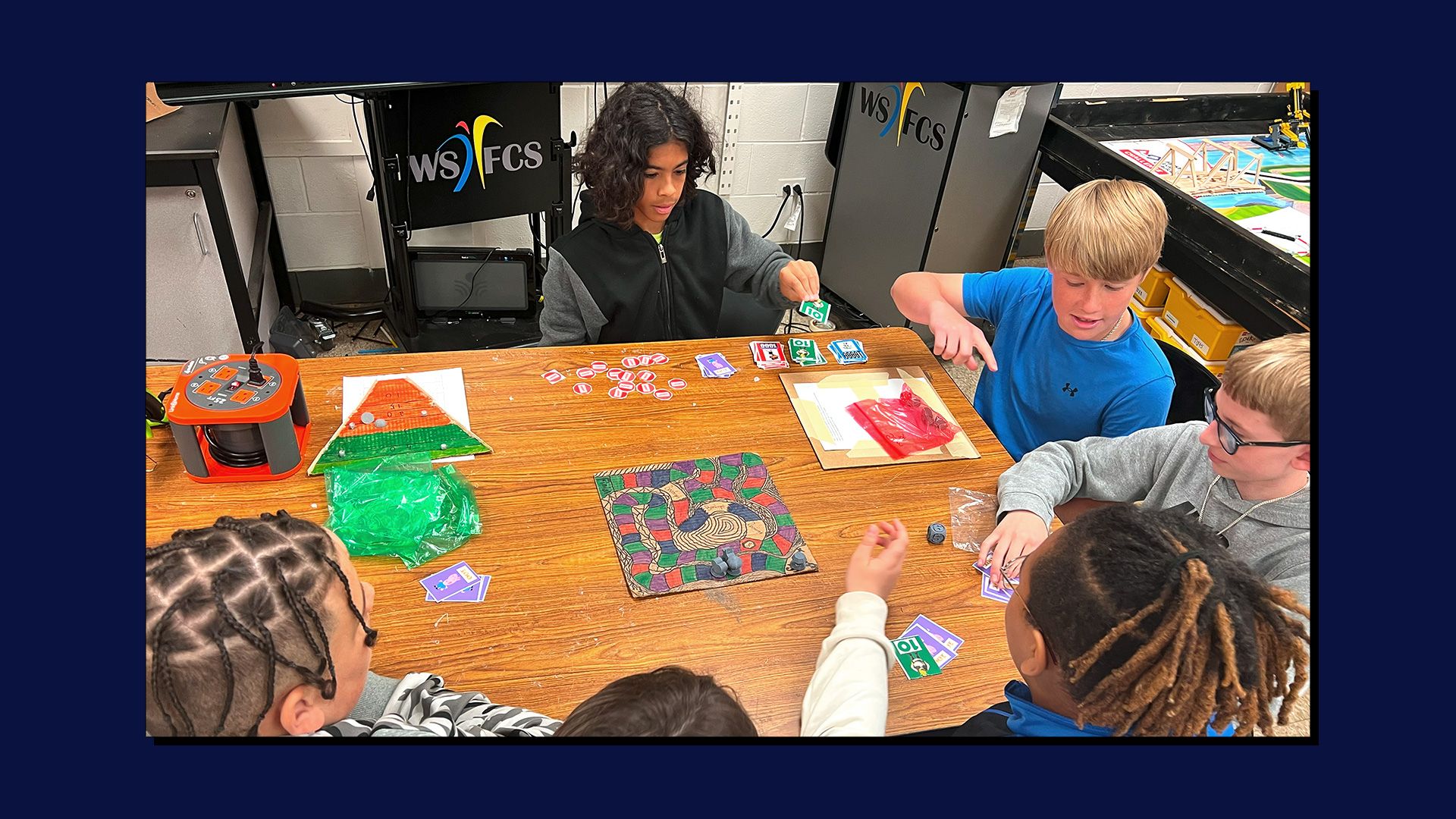 4 students playing a board game with 3D printed dice.