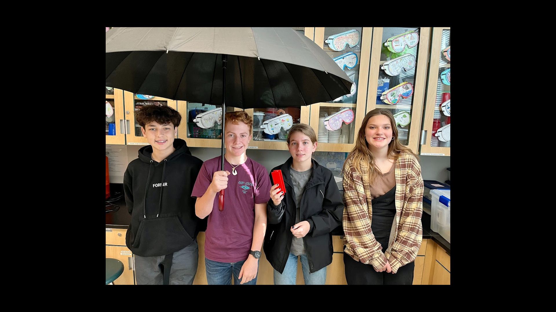 4 students showing their 3D printed wheelchair umbrella holder.
