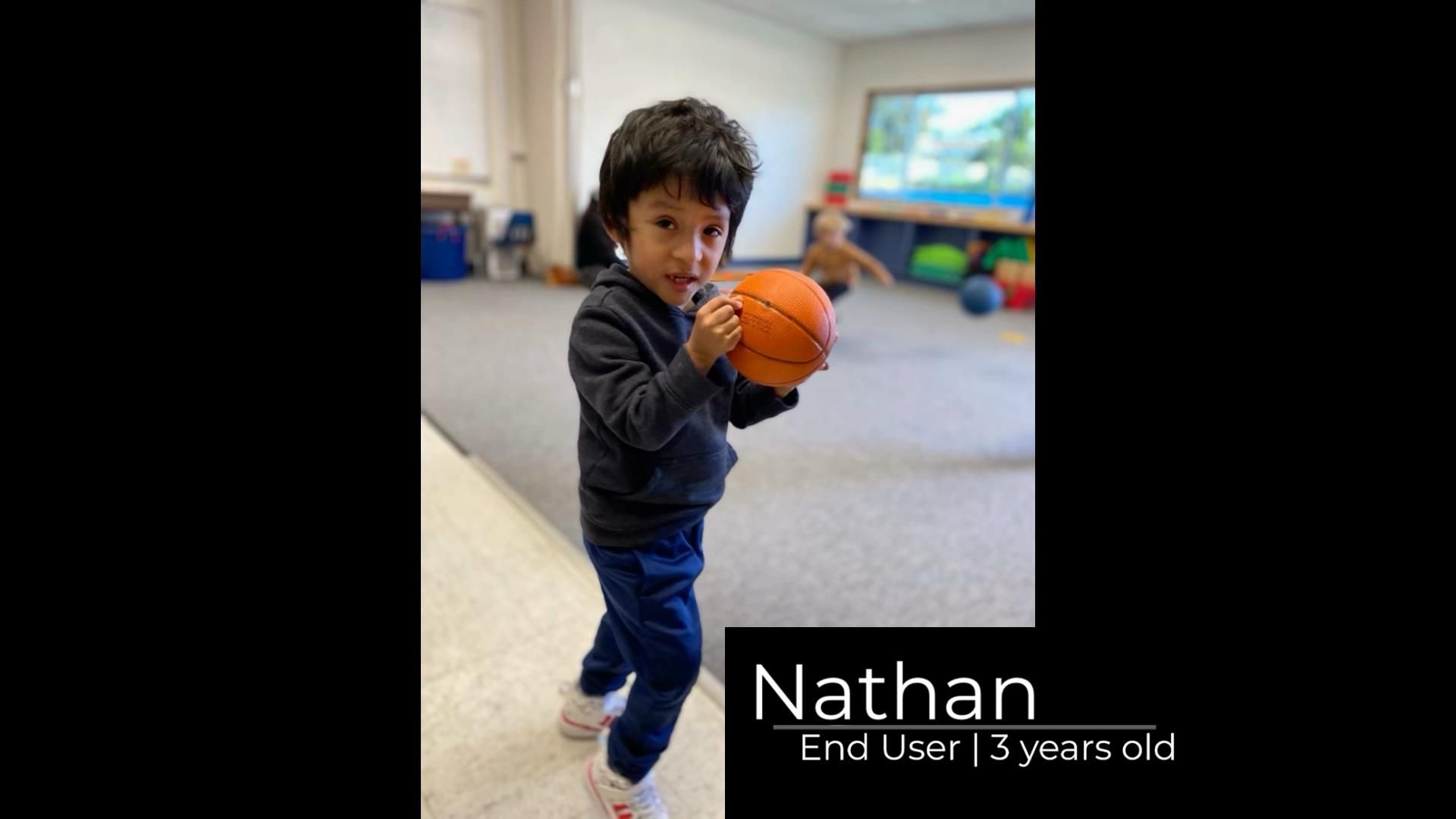 Nathan, 3 year old boy holding a small orange basketball.