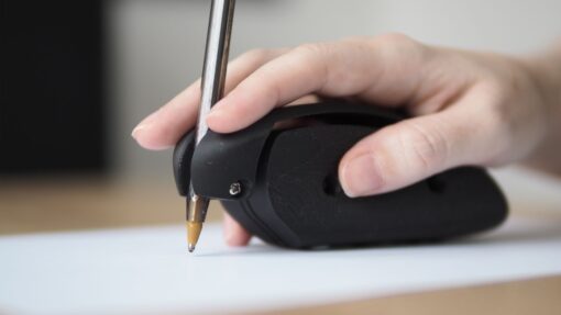 A hand using a 3D printed assistive writing/drawing device, shaped like a mouse.
