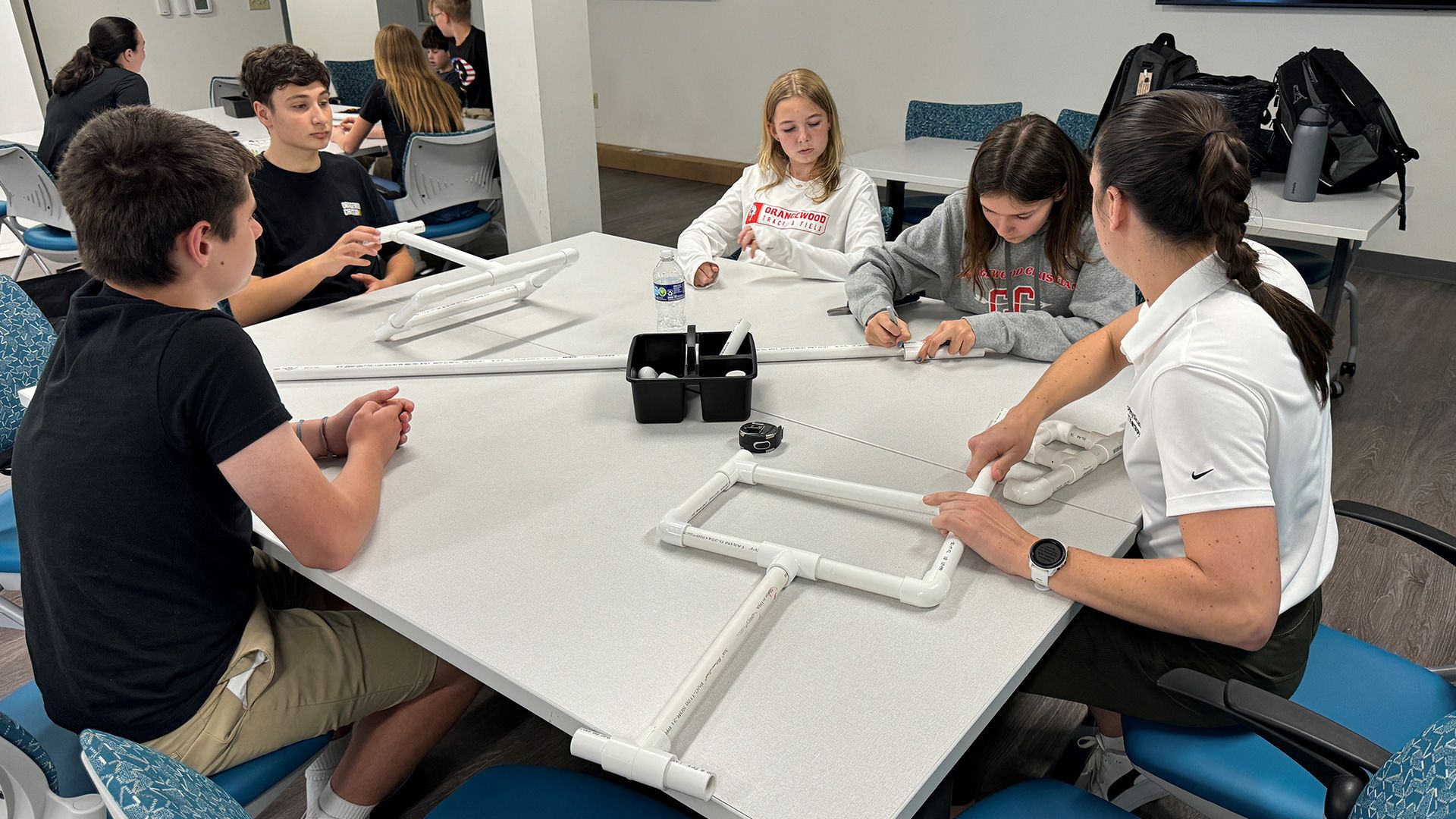 Students sat around a table creating prototypes of an assistive ipad holder