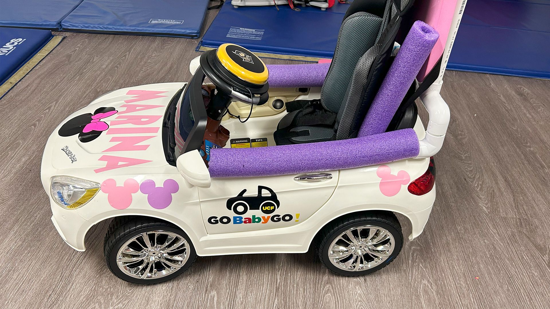 A pink and purple ride-on adaptive car.