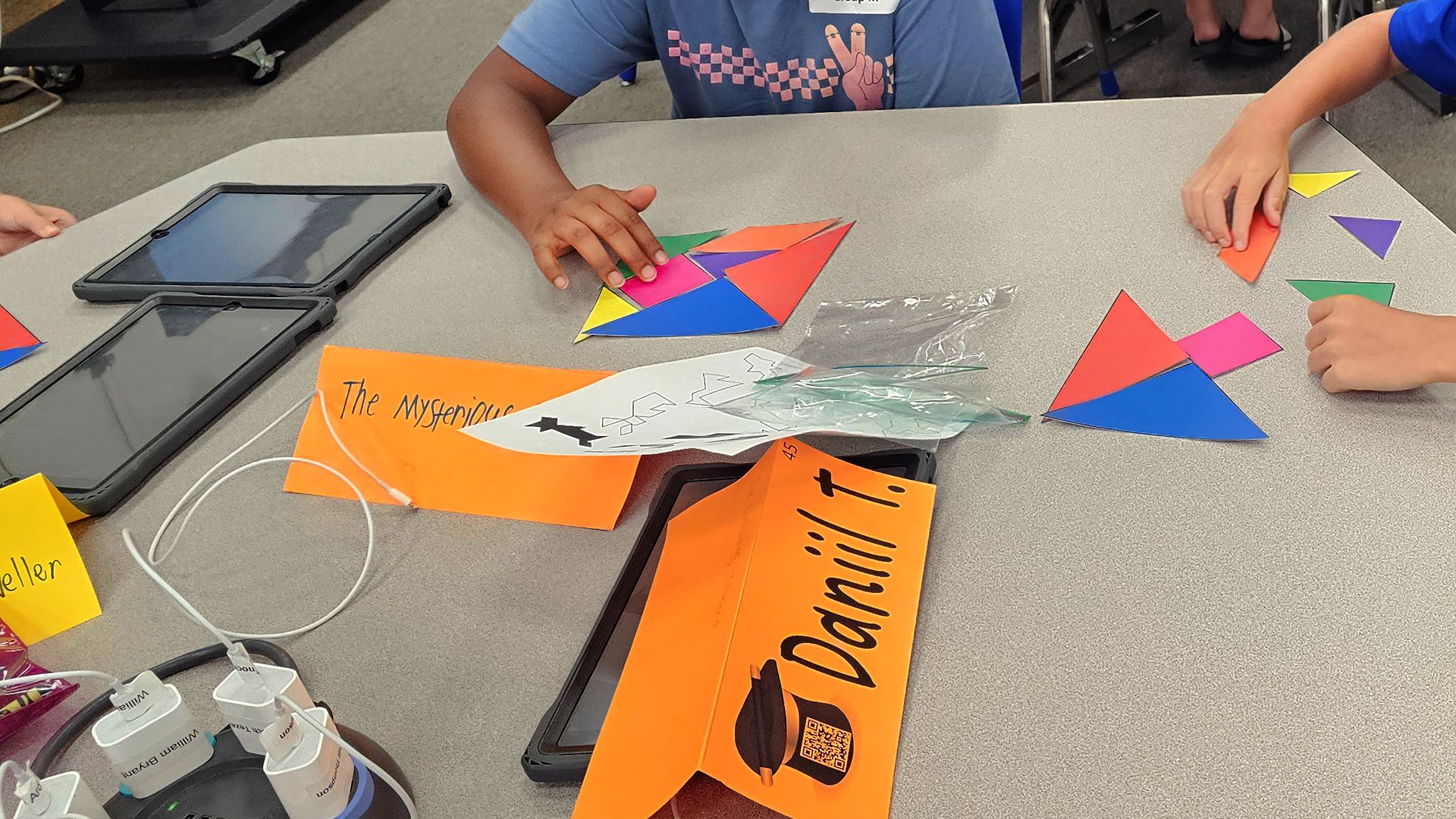 Students manipulating tangram pieces on a table.