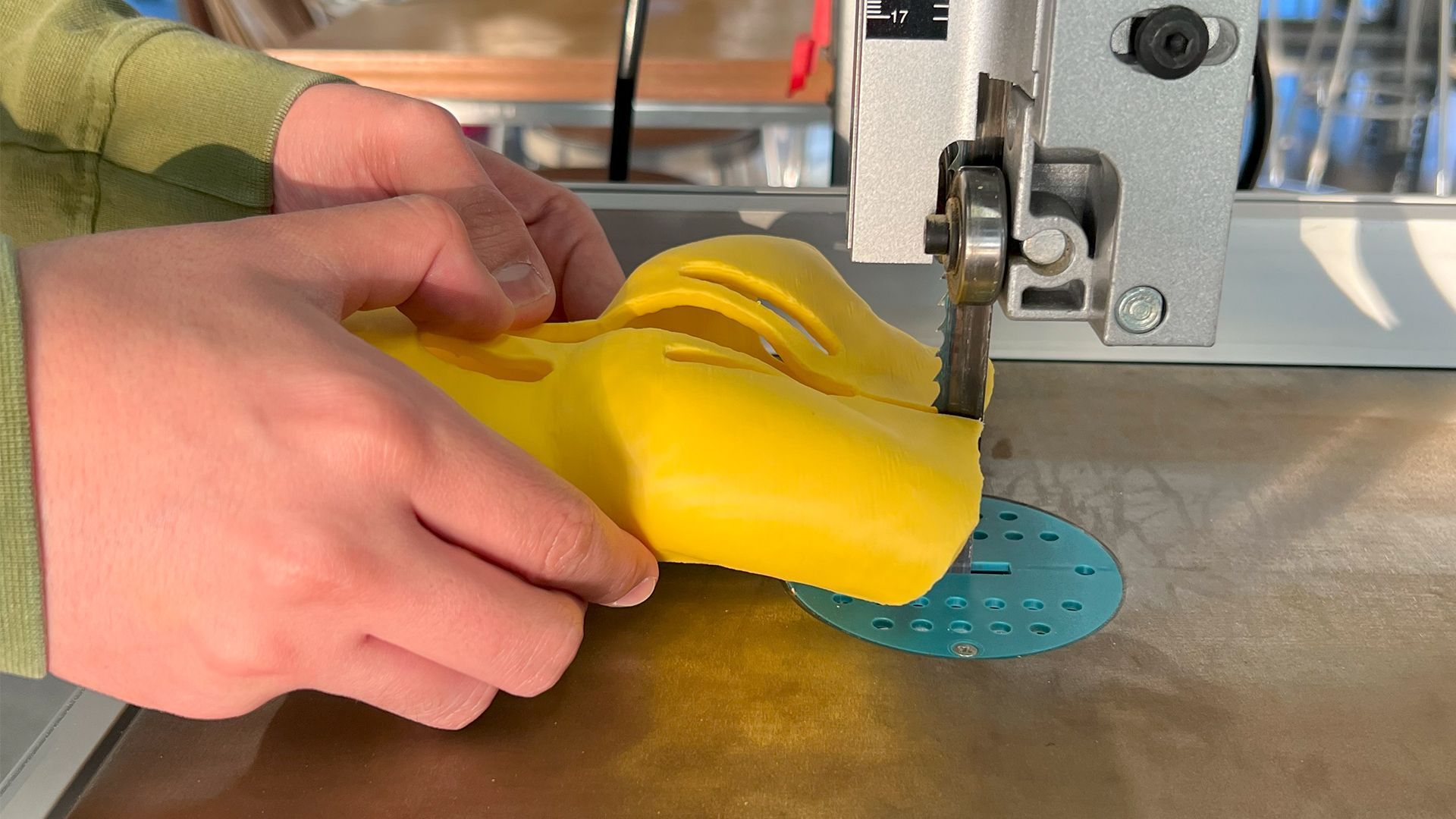 A band saw being used to cut through a 3D printed orthosis.