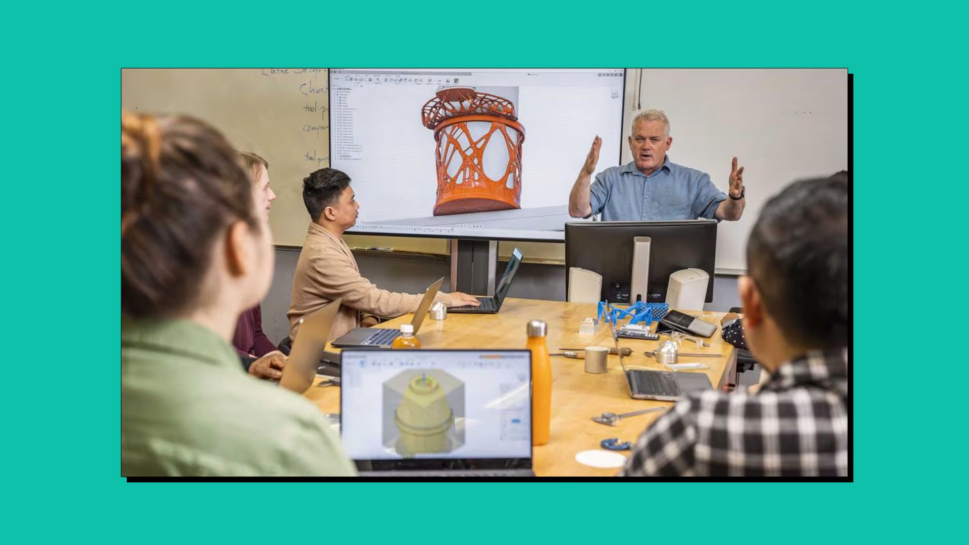 An Autodesk Fusion workshop being run by an instructor. Participants are sat at a table with their laptops.