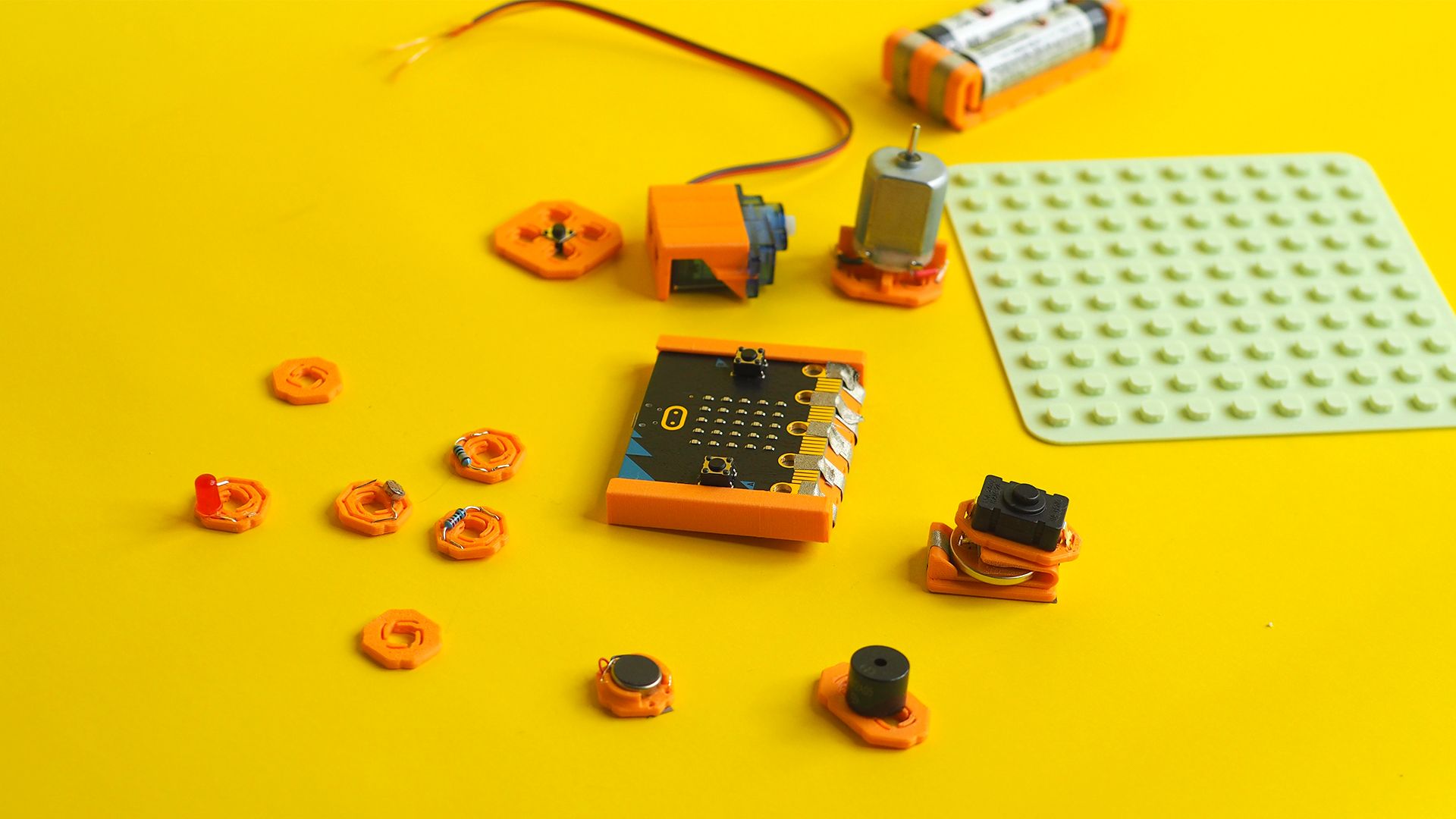 The MakerTrack base kit mounts and grid board spread out onto a yellow background.