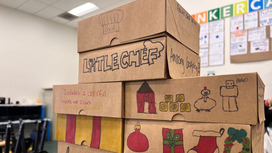 A stack of hand-decorated cardboard boxes labelled “Little Chef,” featuring colourful drawings of barns, ornaments, toys and holiday-themed graphics.