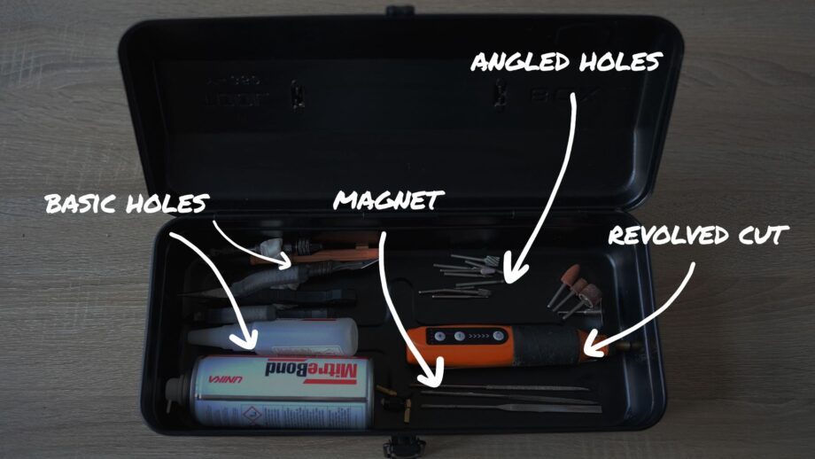 Annotated layout image of tools arranged inside a storage box, with handwritten labels indicating potential storage techniques such as basic holes, angled holes, magnet, and revolved cut.