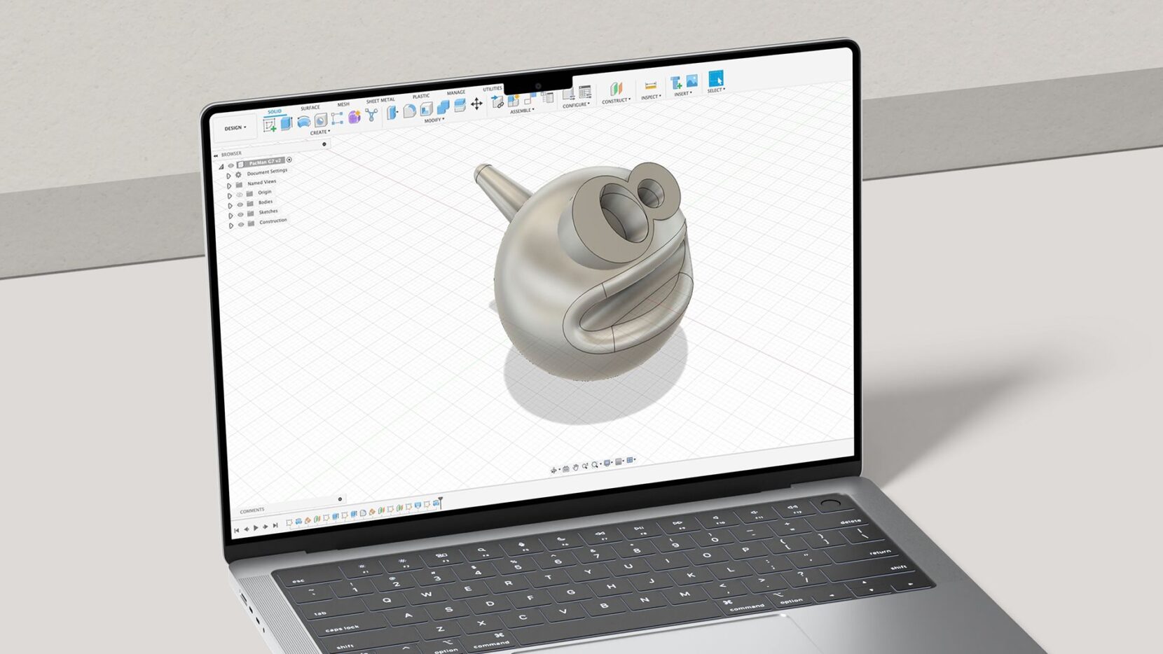 Laptop displaying a character-shaped spinning top with large eyes and an open mouth in Autodesk Fusion.