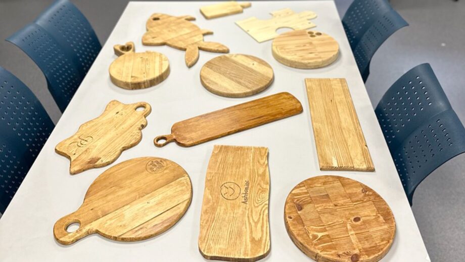 Student-made wooden charcuterie boards in circular, rectangular and animal shapes displayed on a table.